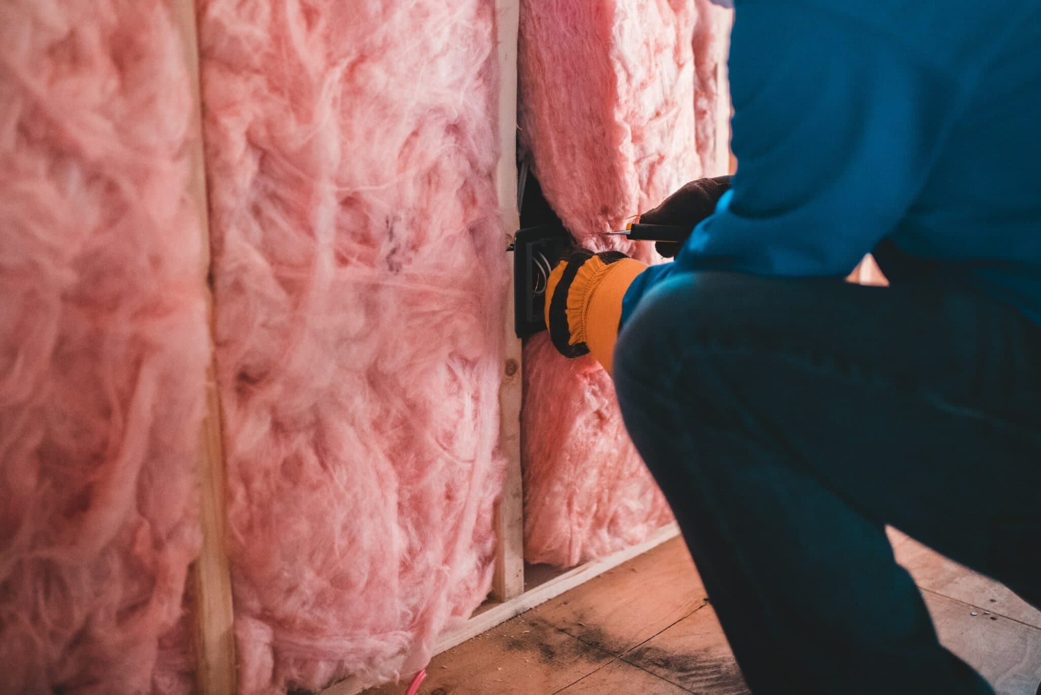 Professional installing batt insulation inside wall framing